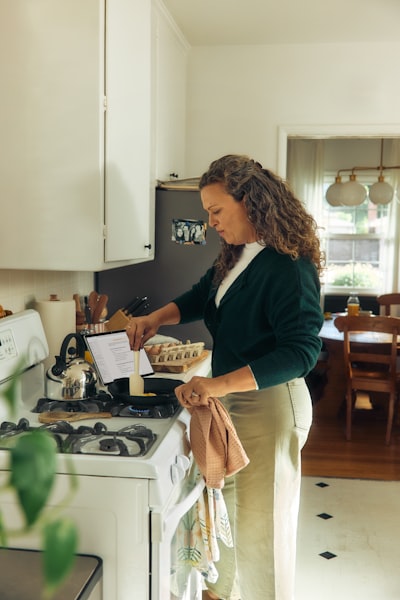 Woman Following Recipe On Tablet In Kitchen. wallpaper preview
