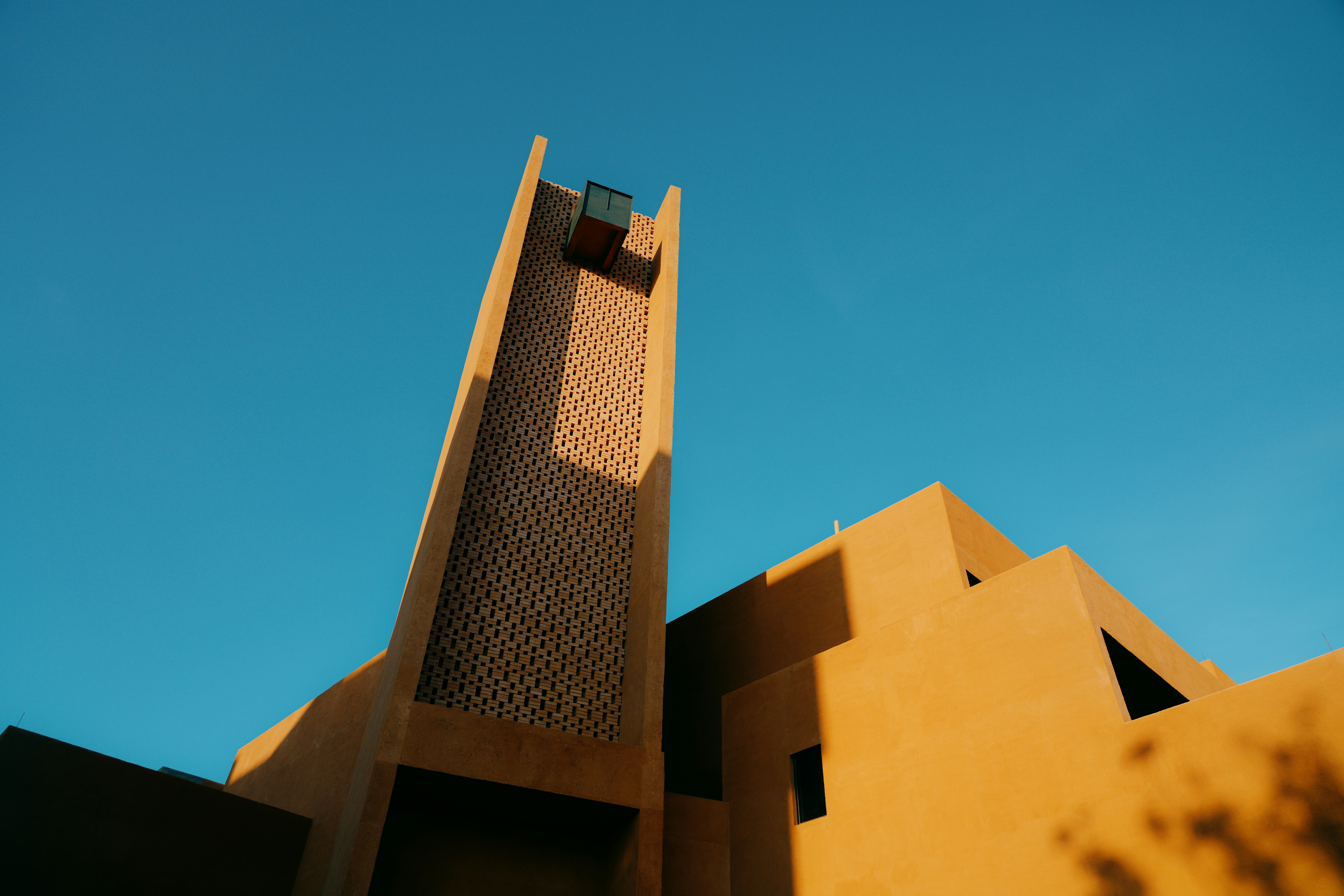 Angular Earth-toned Building With A Prominent Tower Against Blue Sky. HD mobile wallpaper