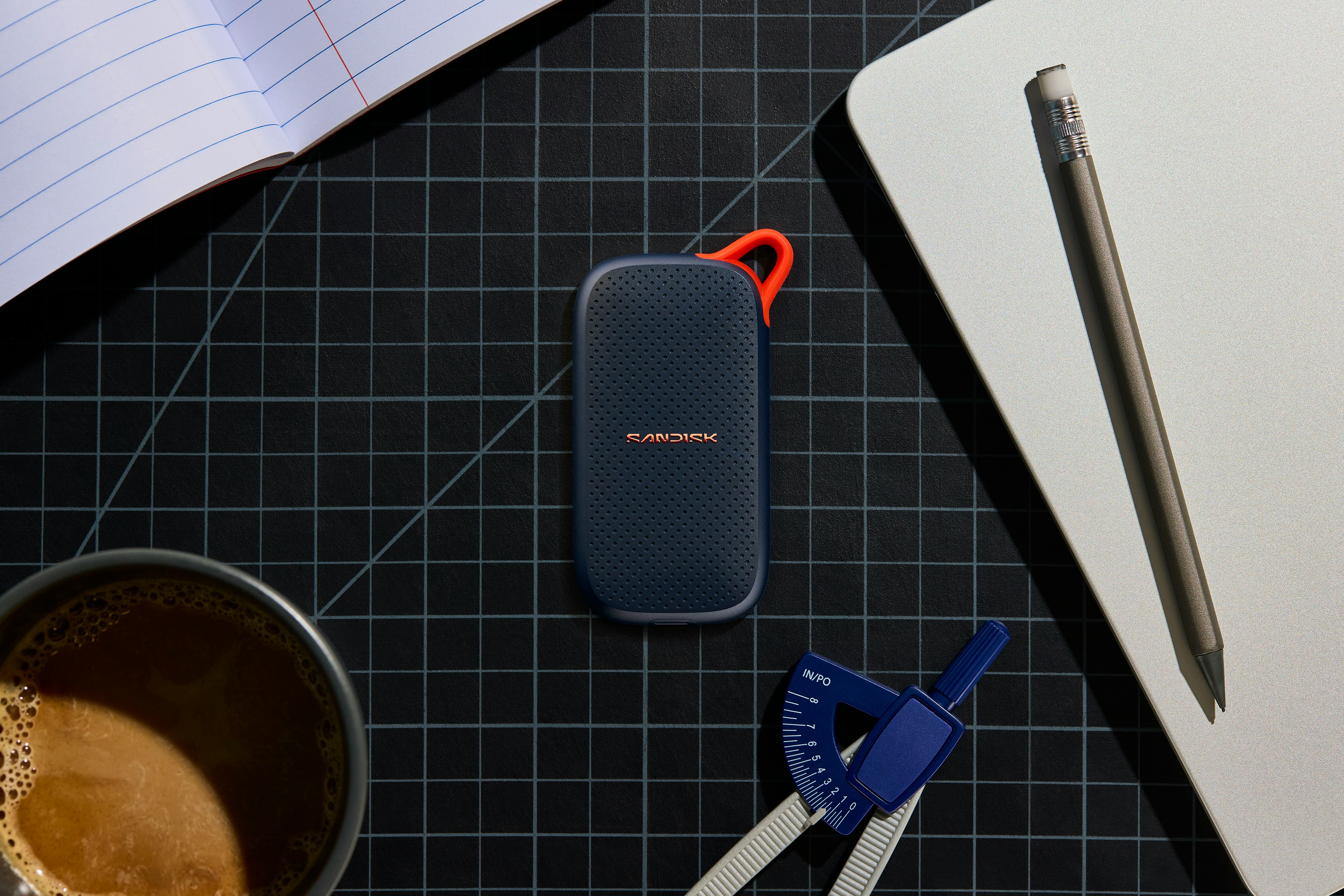Portable Ssd, Coffee, And Stationery On A Grid Mat. HD mobile wallpaper