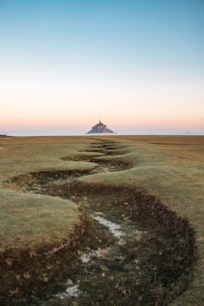 Mont Saint-michel Across A Winding Grassy Plain At Dawn. wallpaper preview