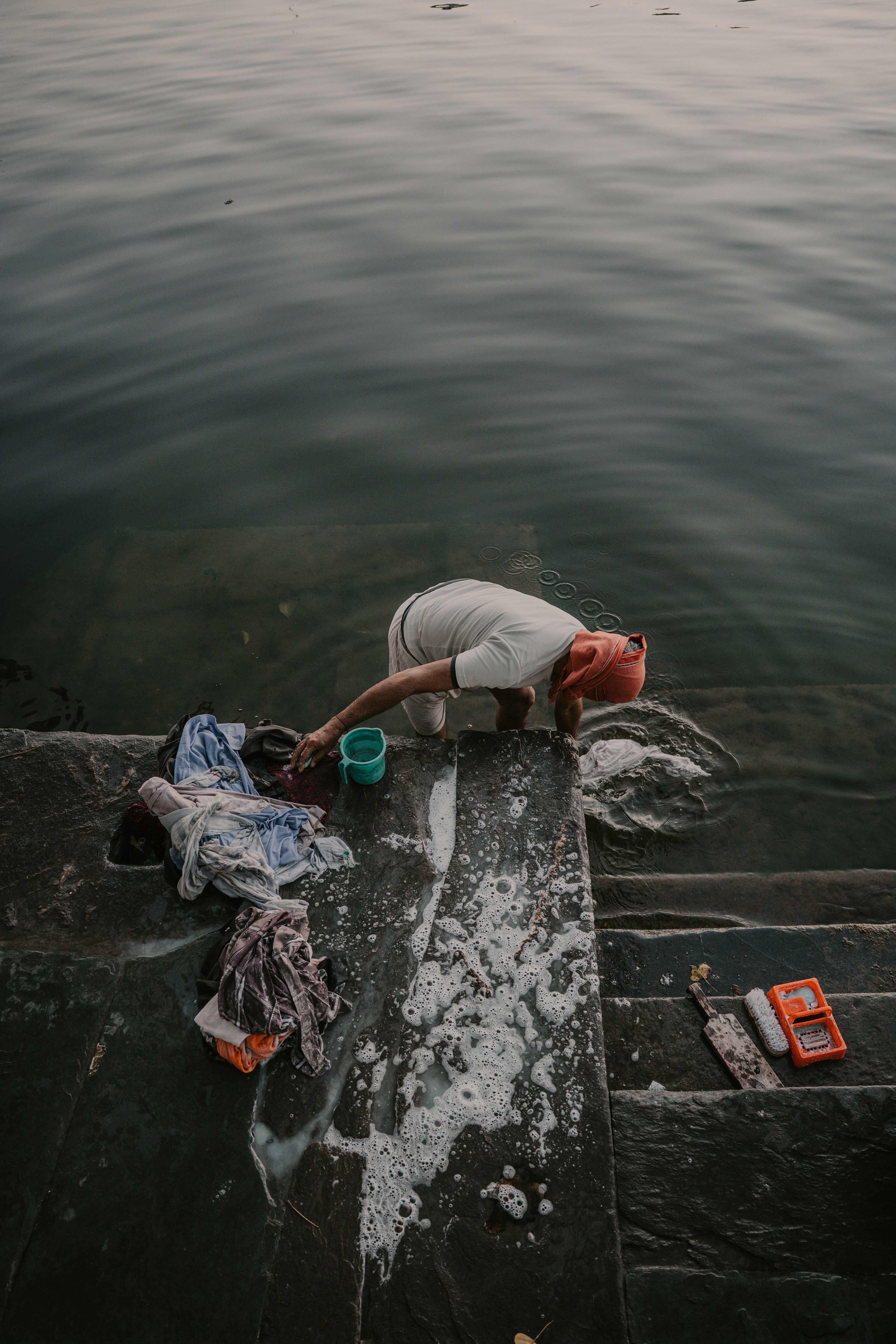 A Person Washing Clothes In The Water On Stone Steps. HD mobile wallpaper