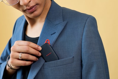 Hand Inserting A Black Electronic Device Into A Blazer Pocket.桌布預覽
