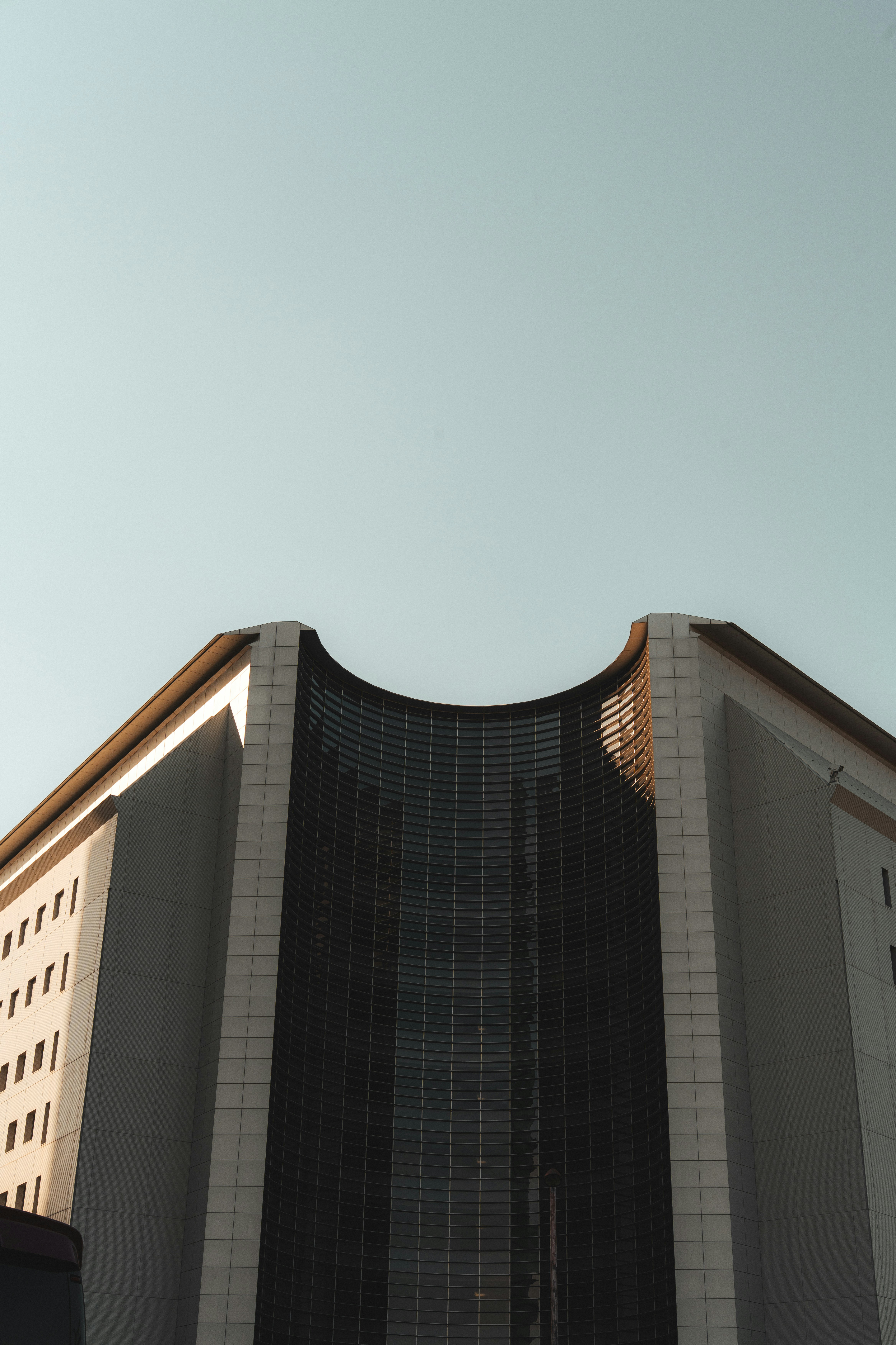 Modern Building With Curved Glass Facade Against A Clear Sky. HD mobile wallpaper