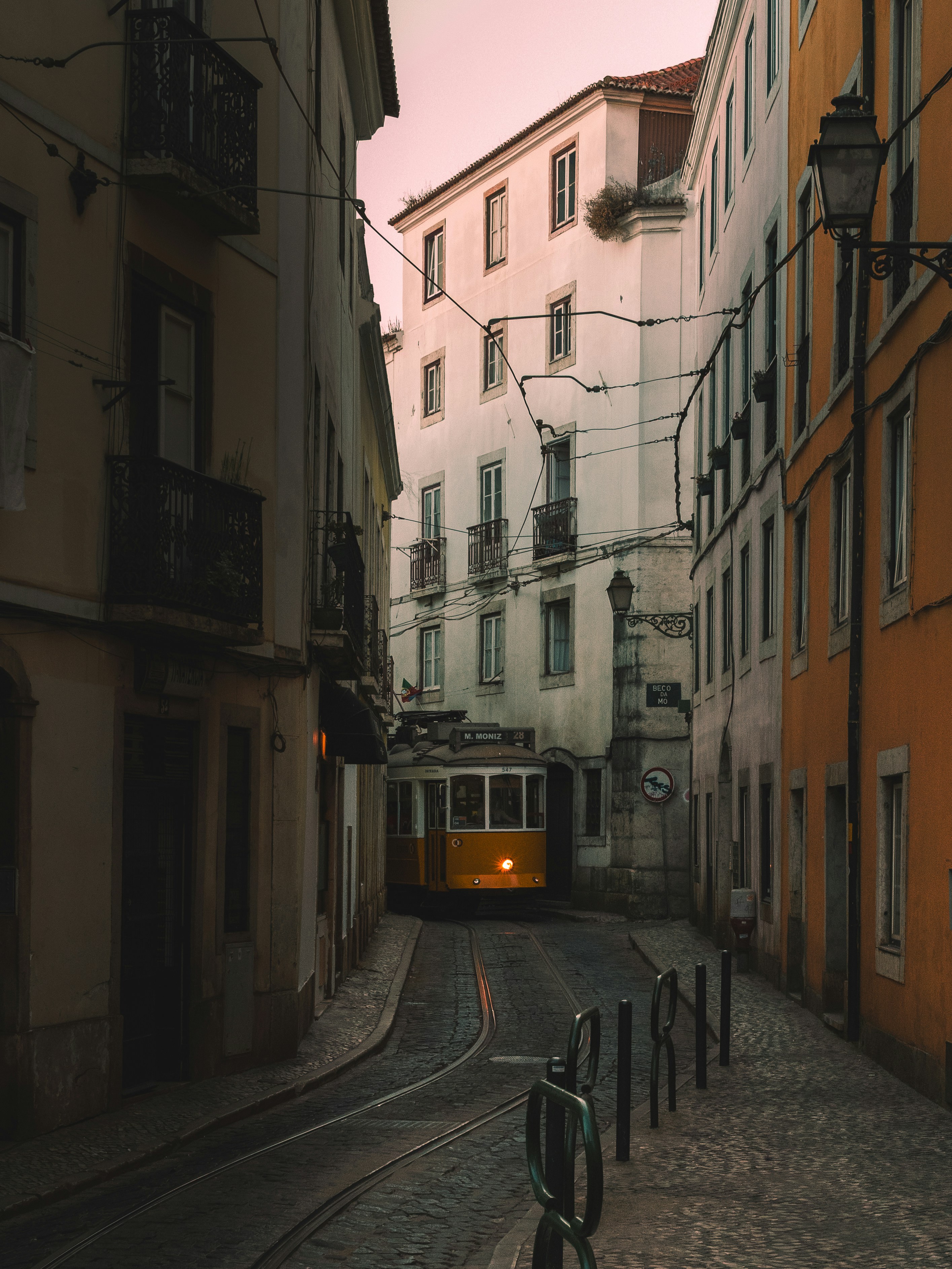 A Yellow Tram On A Narrow Cobblestone Street At Dusk. HD mobile wallpaper