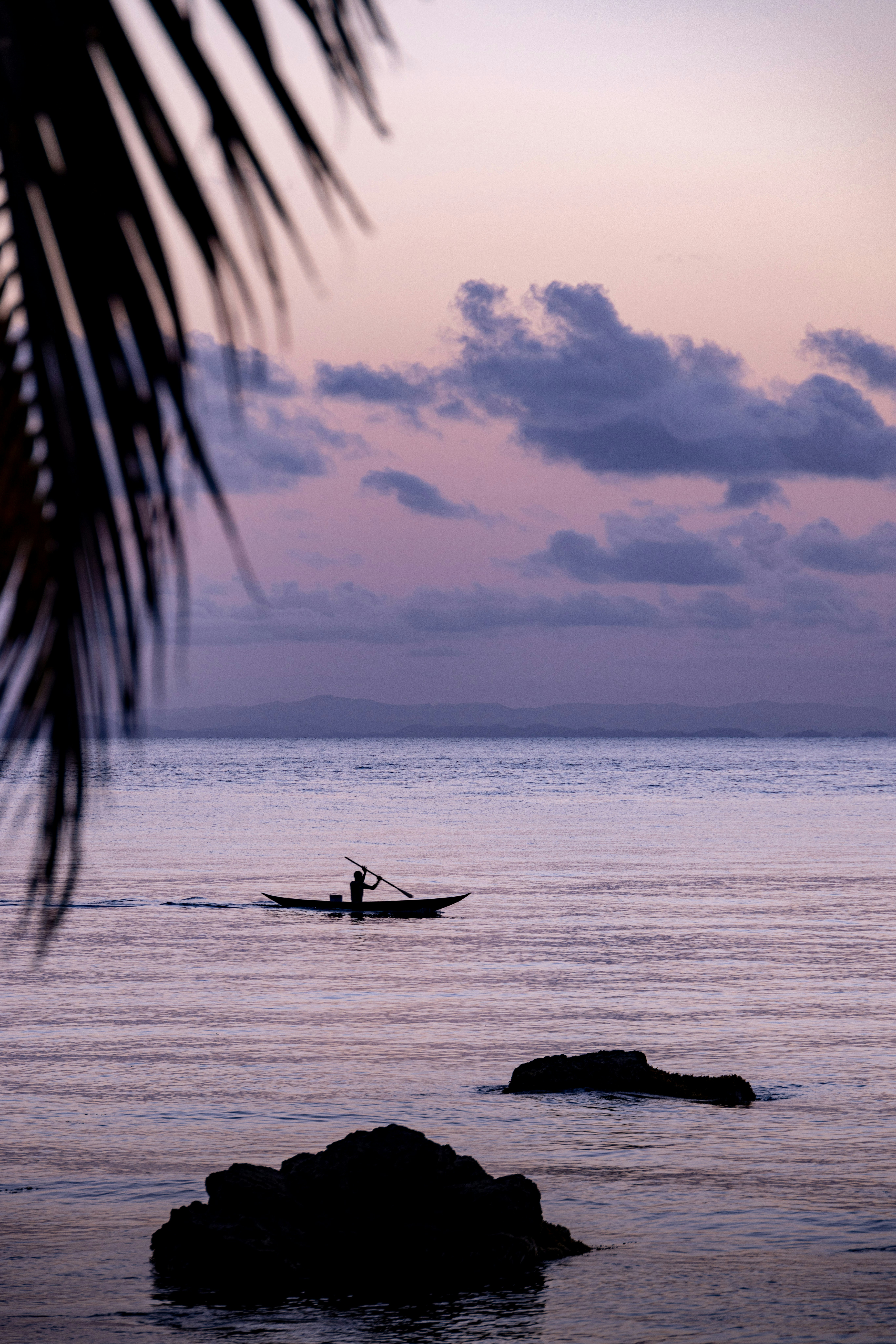 Silhouetted Boatman On Tranquil Sea Under A Colorful Twilight Sky. HD mobile wallpaper