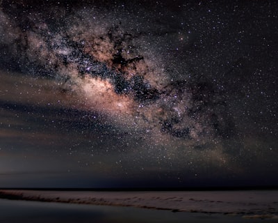 银河在宁静的海岸边的明亮夜空中延伸开来。