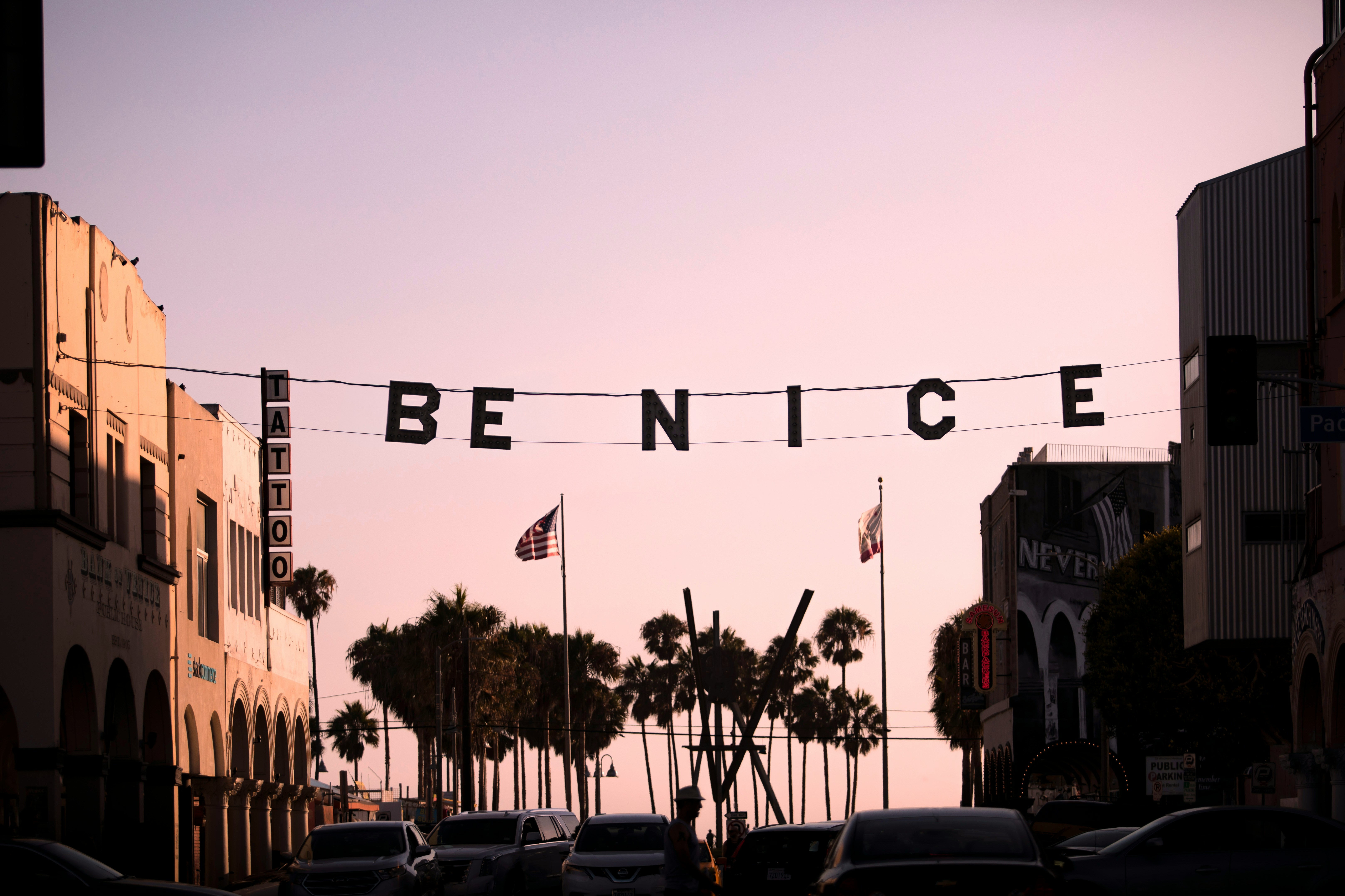 A 'be Nice' Banner Hangs Over A Street At Sunset. HD mobile wallpaper