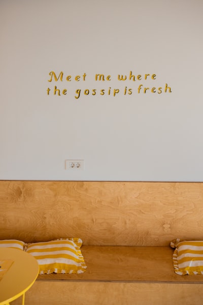 Gold Lettering On White Wall Above Wooden Bench
