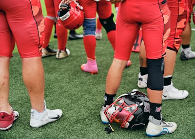 Football Players In Red Uniforms Standing On A Green Field. wallpaper preview