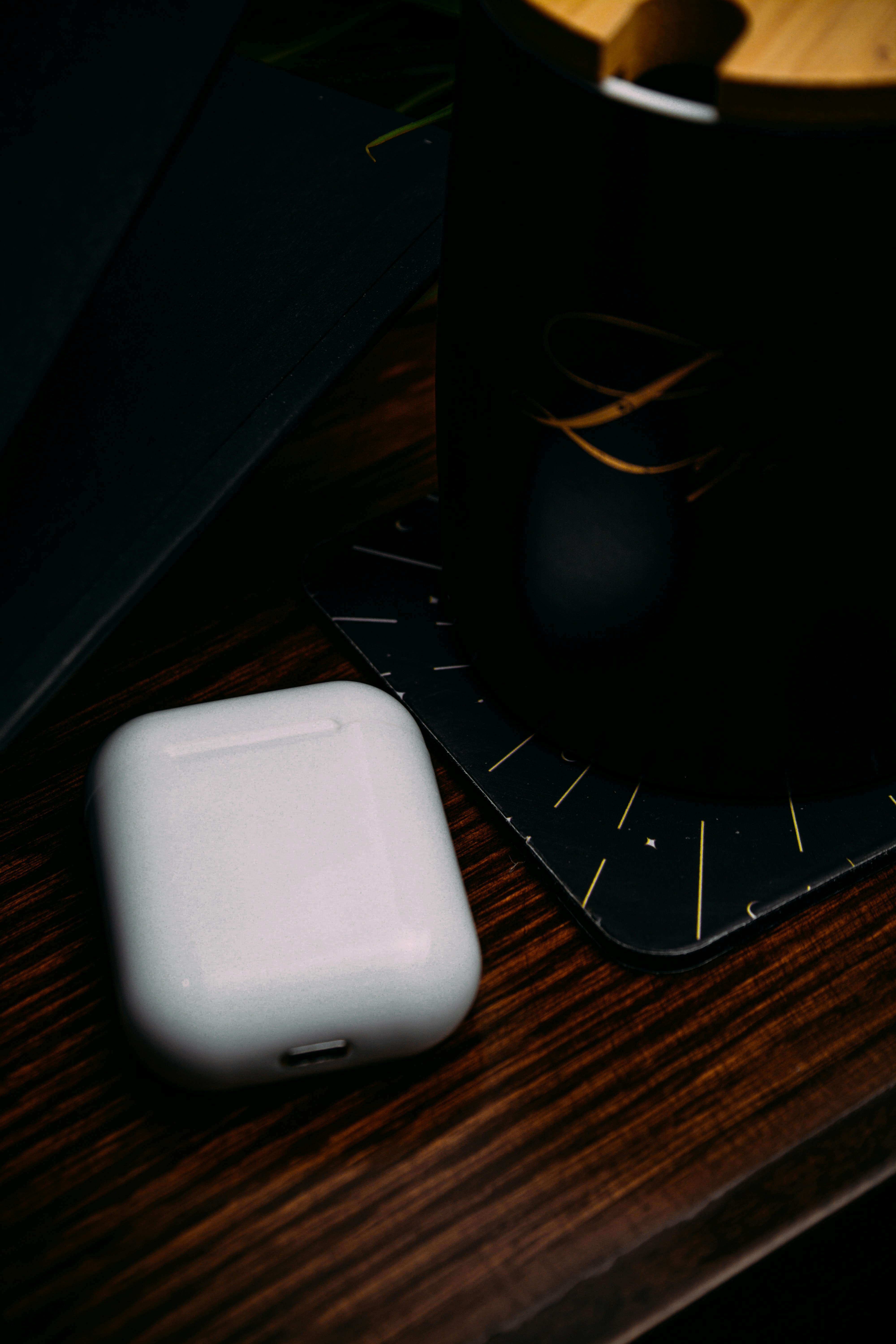 Airpods On Wood Table Beside Black Mug